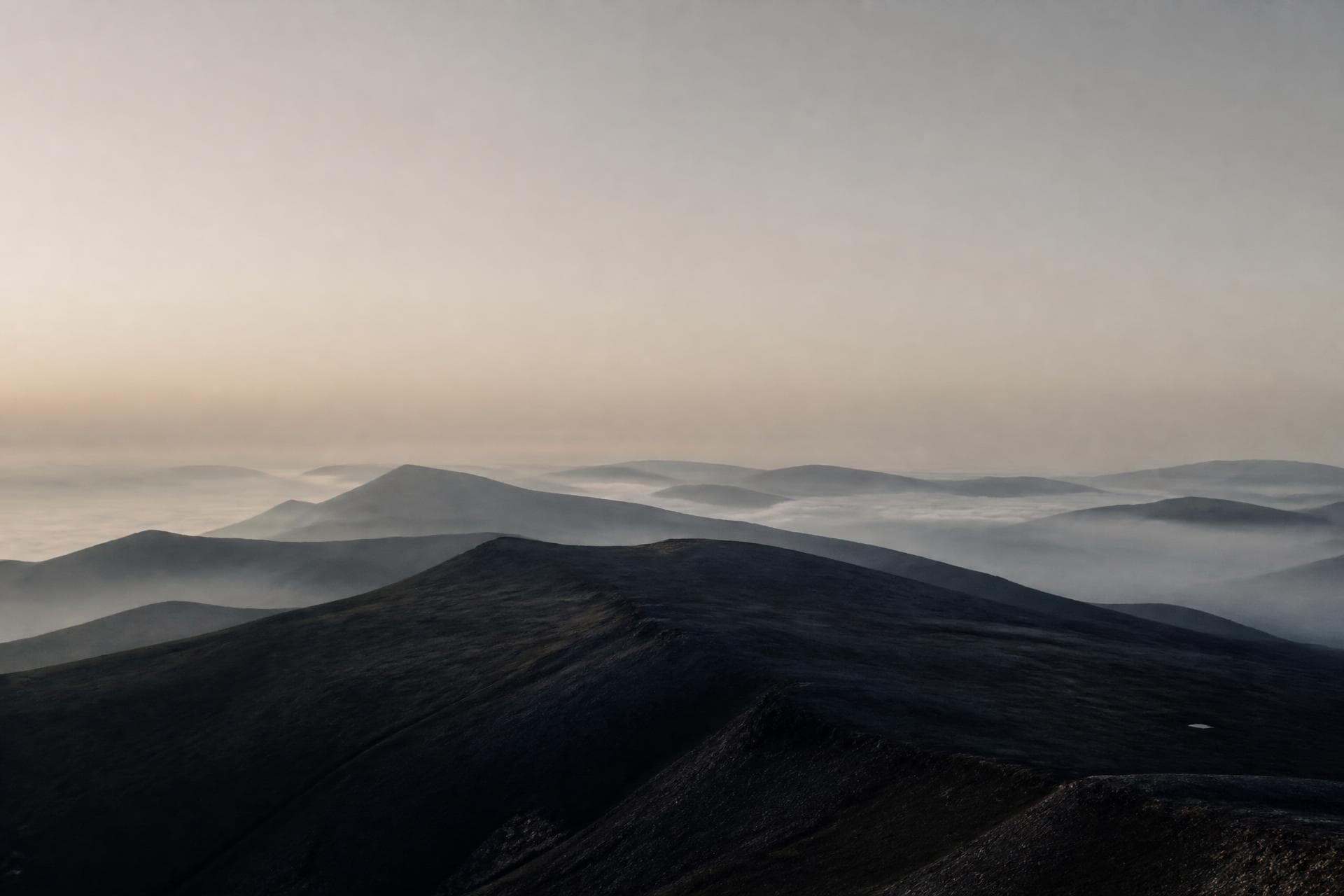 Layered highland ridgelines receding into morning mist above the cloud line